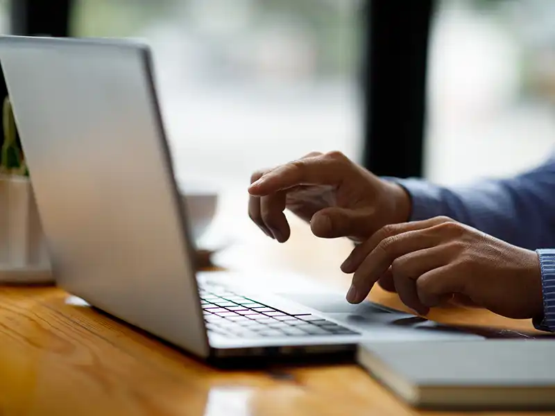 Close up of a person's hands using a laptop
